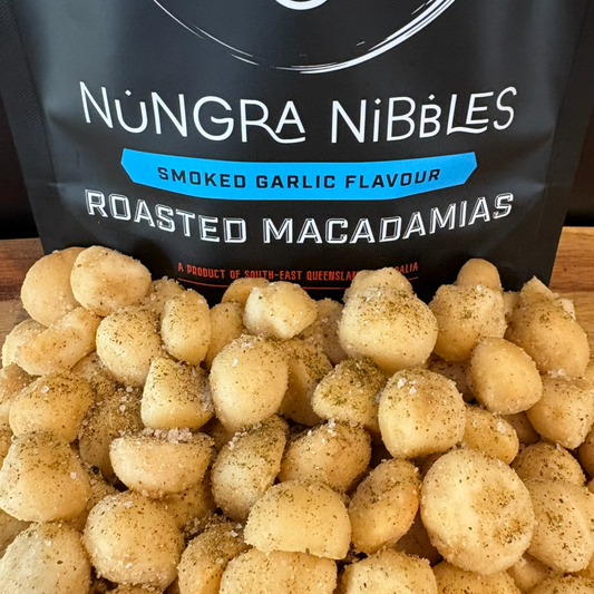 Bag of Nungra Nibbles Smoked Garlic Flavour Roasted Macadamias on a wooden surface